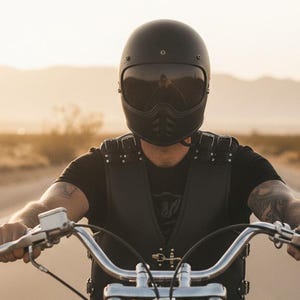 Biker riding motorcycle wearing black leather vest in the desert