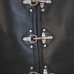 Close-up of side buckle and riveted leather panel on motorcycle vest