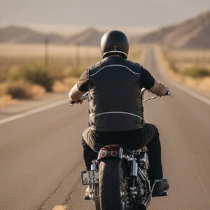 Rear view of biker on the open road wearing black leather club vest