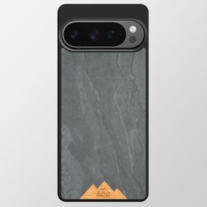 Puede incluir: Funda de teléfono negra con un diseño de textura de piedra gris. La funda presenta un gráfico de montaña de madera con la palabra "MMORE". La cámara del teléfono es visible en la parte superior.