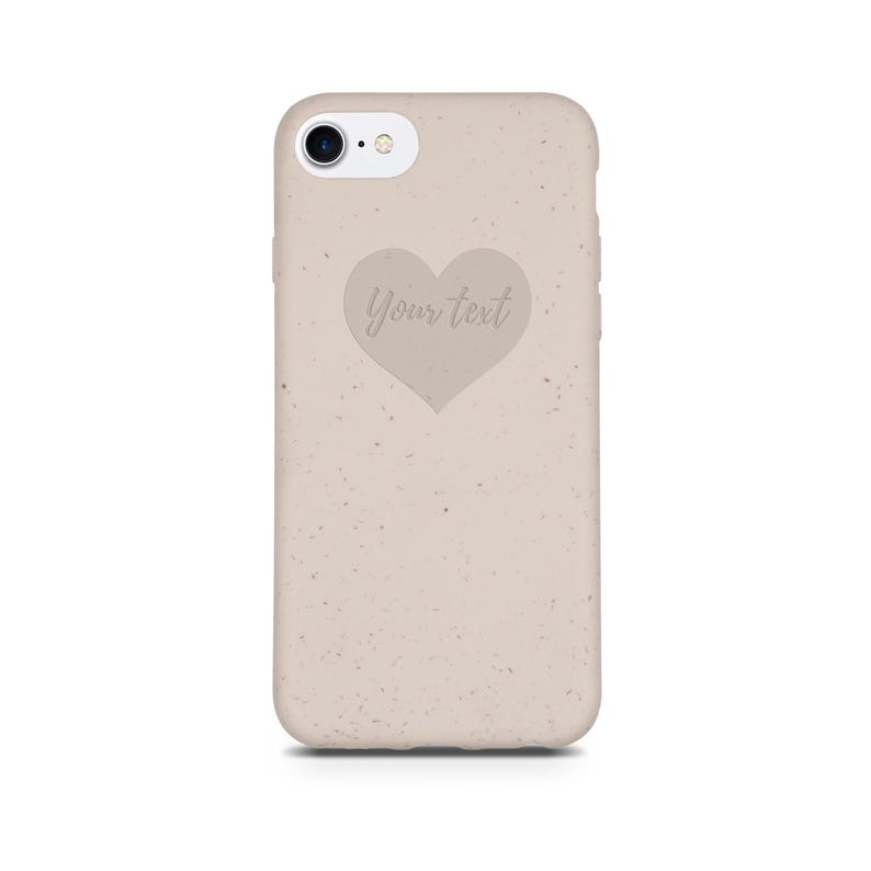 Puede incluir: Una funda de tel&eacute;fono beige con textura moteada y un recorte en forma de coraz&oacute;n con el texto "Your text" en su interior.