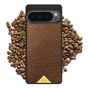 May include: A black phone case featuring a textured brown panel and a gold logo. The case is surrounded by coffee beans. The phone's camera is visible at the top. The logo reads "MMORE".