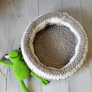 May include: A crocheted pet bed in brown and white with a green crocheted frog toy.
