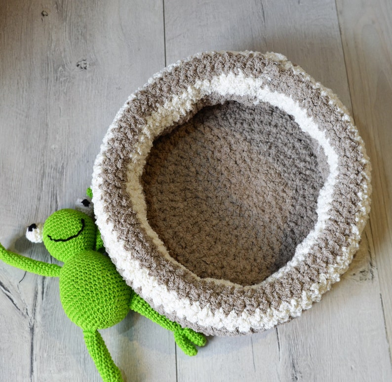 May include: A crocheted pet bed in brown and white with a green crocheted frog toy.