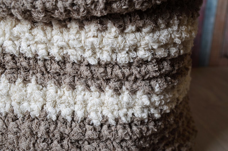 May include: A close-up of a brown and white fluffy rug with a textured surface. The rug is made of soft, looped fibers.