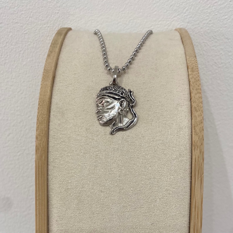 Puede incluir: Un collar de plata con un colgante que presenta un perfil detallado de una persona con un turbante. El colgante est&aacute; en una cadena de plata.