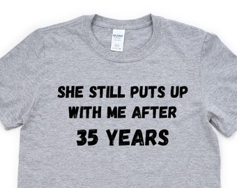 May include: Gray t-shirt with black text that reads "She still puts up with me after 35 years."