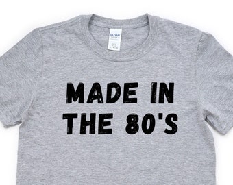 May include: A gray t-shirt with black text that reads "Made in the 80's".