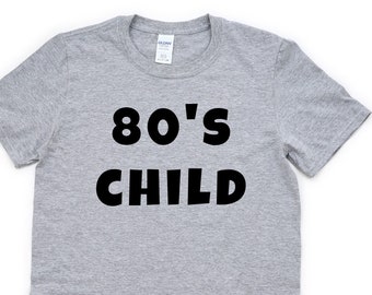 May include: Gray t-shirt with black text that reads "80's CHILD"