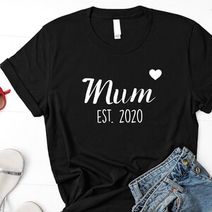 May include: Black t-shirt with white text that reads "Mum Est. 2020" with a small white heart.