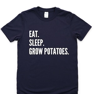 Puede incluir: Una camiseta azul marino con texto blanco que dice "EAT. SLEEP. GROW POTATOES."