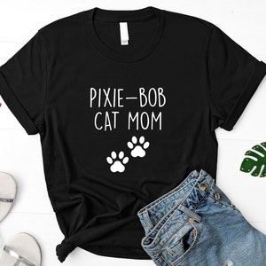 Puede incluir: Camiseta negra con texto blanco que dice "Pixie-Bob Cat Mom" y dos huellas de patas blancas.