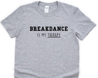 Puede incluir: Camiseta gris con texto negro que dice "Breakdance is my therapy."