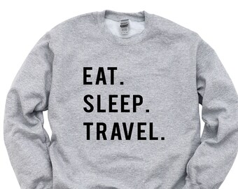 Könnte beinhalten: Grauer Pullover mit dem Aufdruck "EAT. SLEEP. TRAVEL." in Schwarz.