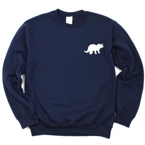 Peut inclure: Un sweat-shirt bleu marine avec une silhouette blanche de tricératops sur le devant.