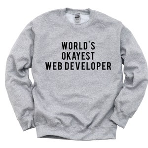 Peut inclure: Un sweat-shirt gris avec le texte "WORLD'S OKAYEST WEB DEVELOPER" imprimé en noir.