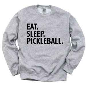 K&ouml;nnte beinhalten: Ein graues Sweatshirt mit dem Text "EAT. SLEEP. PICKLEBALL." in Schwarz gedruckt.