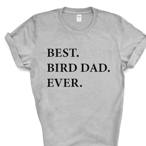 Puede incluir: Una camiseta gris con el texto "BEST. BIRD DAD. EVER." impreso en negro.