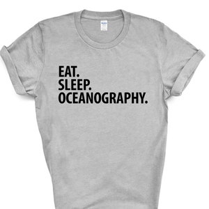以下が含まれることがあります： グレーのTシャツに黒い文字で「Eat. Sleep. Oceanography.」と書いてあります