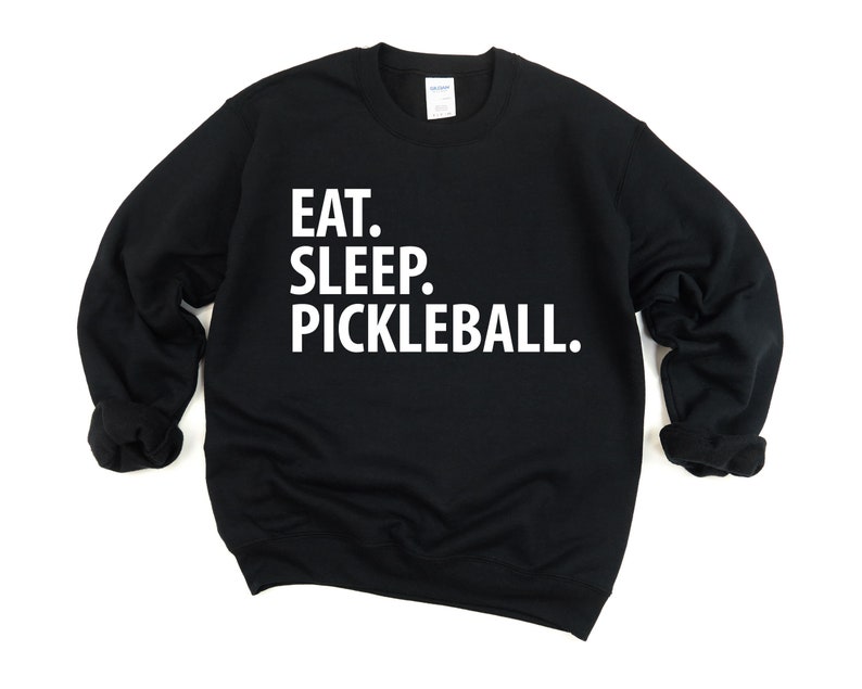 K&ouml;nnte beinhalten: Schwarzer Pullover mit wei&szlig;em Text, der "Essen. Schlafen. Pickleball." lautet.