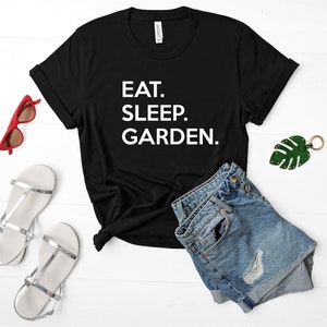 May include: Black t-shirt with white text that reads "EAT. SLEEP. GARDEN."