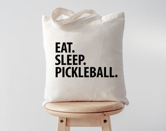 Könnte beinhalten: Eine weiße Stofftasche mit schwarzem Text, der "EAT. SLEEP. PICKLEBALL." lautet.