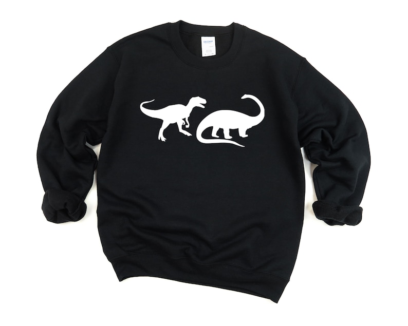 K&ouml;nnte beinhalten: Schwarzer Pullover mit einer wei&szlig;en Silhouette von zwei Dinosauriern auf der Vorderseite.