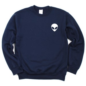 May include: A navy blue sweatshirt with a white alien face graphic on the front.