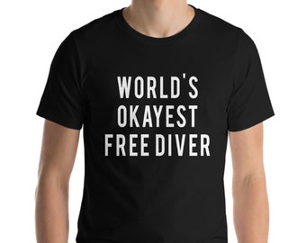 Könnte beinhalten: Schwarzes T-Shirt mit dem weißen Text "WORLD'S OKAYEST FREE DIVER". Das T-Shirt hat einen Rundhalsausschnitt und scheint aus einem weichen Material zu sein. Der Text ist mittig auf der Vorderseite des T-Shirts platziert.