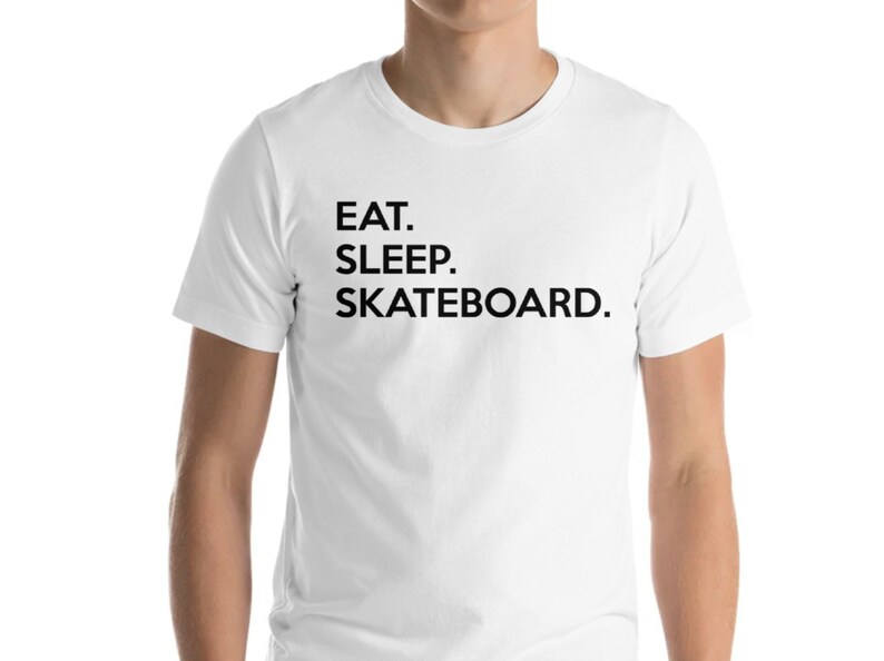 K&ouml;nnte beinhalten: Wei&szlig;es T-Shirt mit schwarzem Text, der "EAT. SLEEP. SKATEBOARD." lautet.