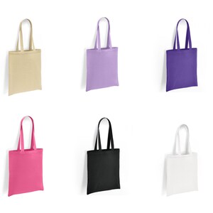 May include: Six tote bags in different colours: beige, lavender, purple, pink, black, and white. The bags are made of canvas and have a simple design.