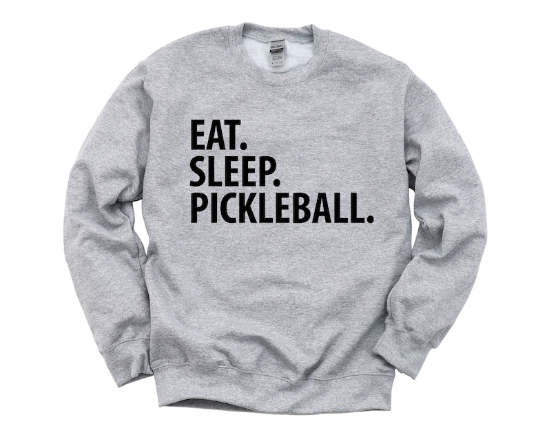 K&ouml;nnte beinhalten: Ein graues Sweatshirt mit dem Text "EAT. SLEEP. PICKLEBALL." in Schwarz gedruckt.