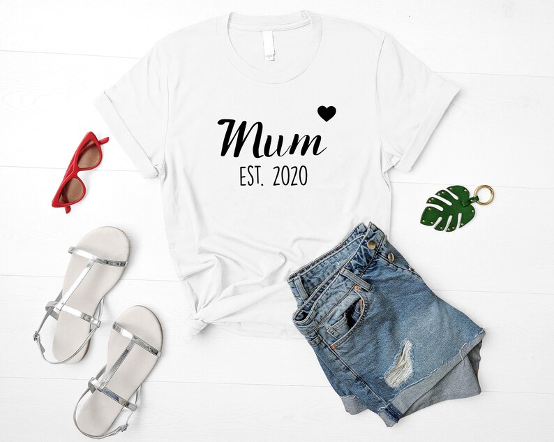 May include: White t-shirt with black text that reads "Mum Est. 2020" with a small black heart.