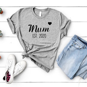May include: Gray t-shirt with the text "Mum Est. 2020" and a small black heart.