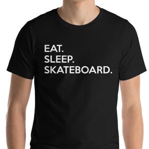 K&ouml;nnte beinhalten: Schwarzes T-Shirt mit wei&szlig;em Text, der "Essen. Schlafen. Skateboarden." lautet.