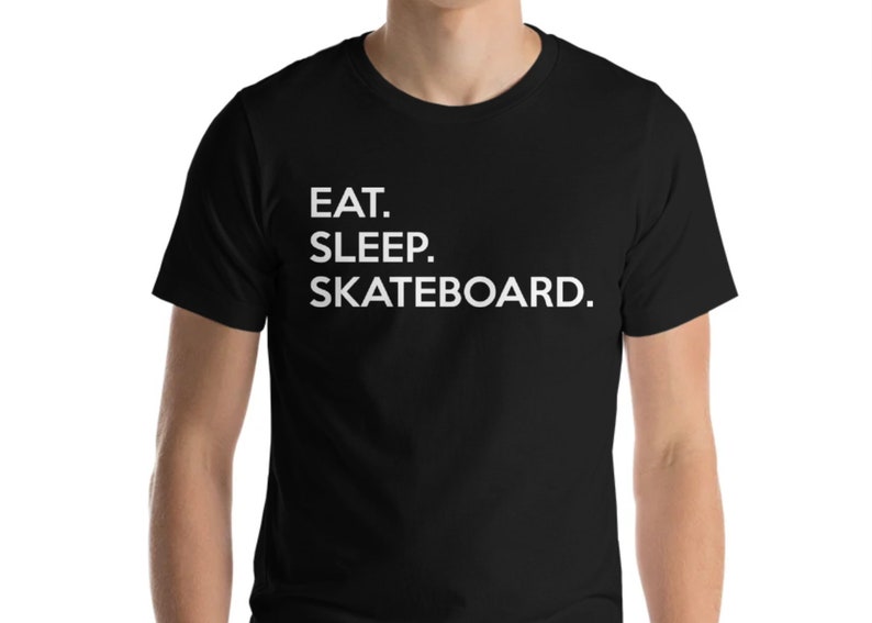 K&ouml;nnte beinhalten: Schwarzes T-Shirt mit wei&szlig;em Text, der "Essen. Schlafen. Skateboarden." lautet.