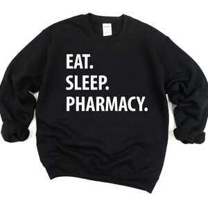 May include: Black sweatshirt with white text that reads "Eat. Sleep. Pharmacy."