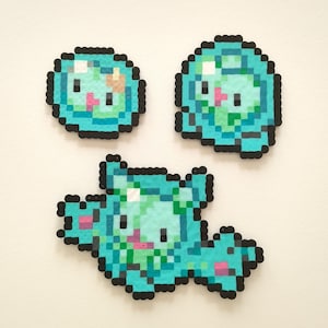 May include: Three blue and green pixel art characters with black outlines. The characters are in the shape of a frog, a turtle, and a fish. The characters are made of small plastic beads.