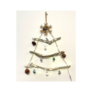 May include: A rustic Christmas tree made from driftwood branches, decorated with pine cones, white and teal ornaments, and string lights.