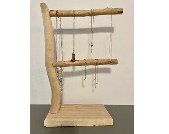 May include: A wooden jewelry stand with two levels for hanging necklaces and earrings. The stand is made of natural driftwood and has a rustic, organic look.
