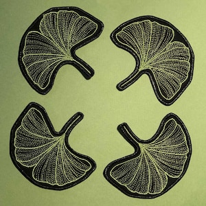 Può includere: Quattro toppe di tessuto nero con un disegno di foglia di ginkgo ricamato in verde.