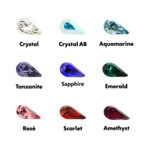 以下が含まれることがあります： Crystal、Crystal AB、Aquamarine、Tanzanite、Sapphire、Emerald、Ros&eacute;、Scarlet、Amethystとラベル付けされた、様々な色の9つの洋梨型ファセットクリスタルのグリッド。各クリスタルは、独特の光の屈折と鮮やかな色合いを示しています。