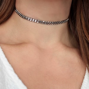 Może przedstawiać: Srebrny naszyjnik choker na szyi osoby.