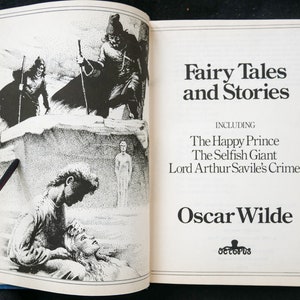 May include: A hardback book open to a double-page spread. The left page has a black and white illustration. The right page displays the title "Fairy Tales and Stories" and the author's name, Oscar Wilde.