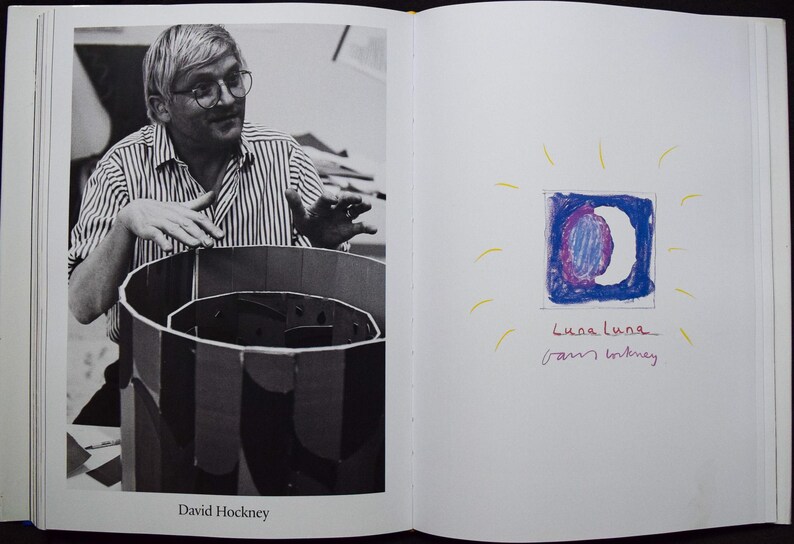 May include: Black and white photograph of David Hockney with a striped shirt, looking at a cylindrical cardboard structure. On the facing page, a drawing of a moon in a square with the text "Luca Luna" and "Sam Whitney".