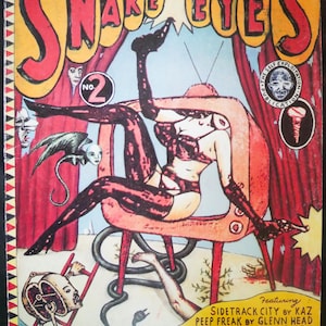 May include: Comic book cover titled "Snake Eyes" with a surreal illustration. The artwork features a figure in lingerie, a snake, and various other bizarre elements. The cover includes text such as "No. 2" and the names of the featured artists.