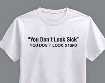 May include: White crew neck t-shirt with the text "You Don't Look Sick" and "You Don't Look Stupid" printed in black. The shirt is made of a soft material and is suitable for casual wear.