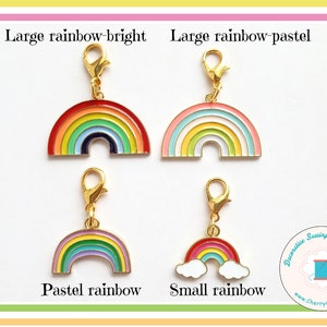 May include: Four rainbow-themed charms with gold-colored clasps. The charms are in various sizes and color schemes, including bright and pastel rainbows. Text on the image reads "Large rainbow-bright", "Large rainbow-pastel", "Pastel rainbow", and "Small rainbow".