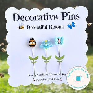 May include: Decorative pins with bee, flower, and butterfly designs. The pins are on a white card with the text "Decorative Pins" and "Bee-utiful Blooms." The card also includes the text "Sewing * Quilting * Counting Pin" and the website www.CherryChickbiz.