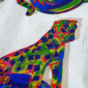 May include: A white fabric with a repeating pattern of a stylized 'C' in a circle. The fabric also features a colorful cheetah print with red, yellow, blue, and green colors.